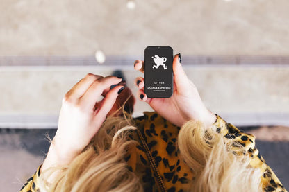 A person holding a tin of Littos double expresso coffee chewable. The person has blonde hair, black fingernails, and is wearing a yellow leopard-print top.
