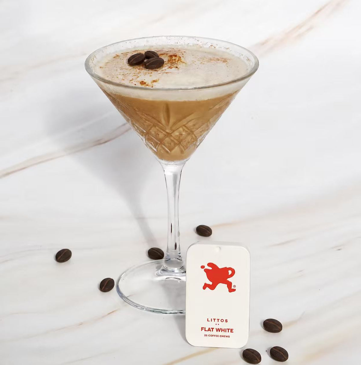 A flat white style coffee drink styled alongside the Littos Flat White Coffee Chews tin.